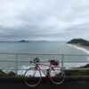 海沿いの高台からロードバイクと入江を望む景色