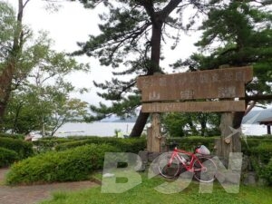 「山中湖」と書かれた木製看板の前に停めた赤いロードバイク