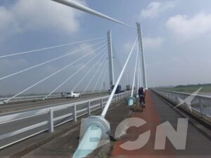 斜張橋の主塔とケーブル、橋上を走るロードバイク