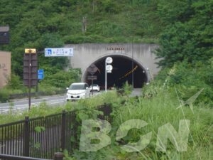 山あいのトンネル入口に向かう道路と案内標識