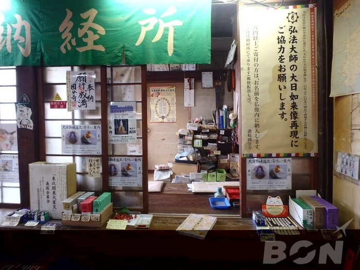 The counter of a temple stamp office with a green sign reading Nokyosho
