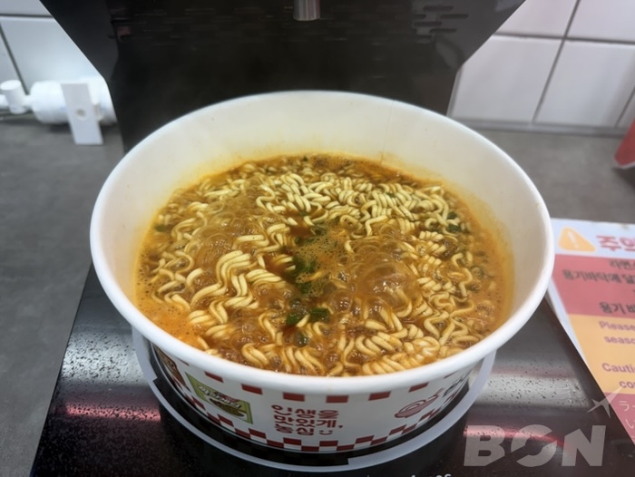 Kラーメンコンビニ 調理器でお湯を注入する様子